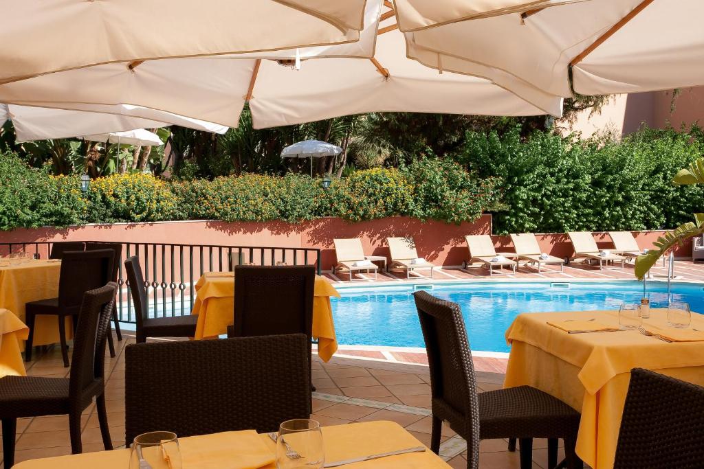 a restaurant with tables and umbrellas next to a pool at Imperial Hotel Tramontano in Sorrento