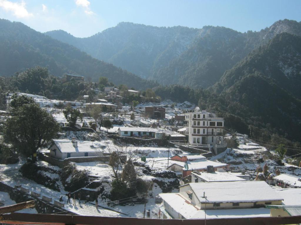 a town covered in snow with mountains in the background at Janardan Resort Pangot Nainital in Nainital