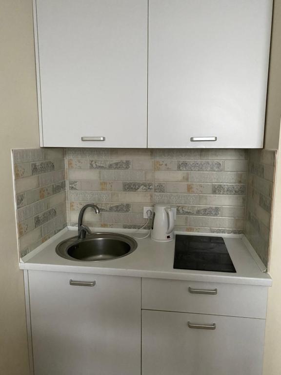 a kitchen counter with a sink and white cabinets at BYSmartHouse in Kyiv