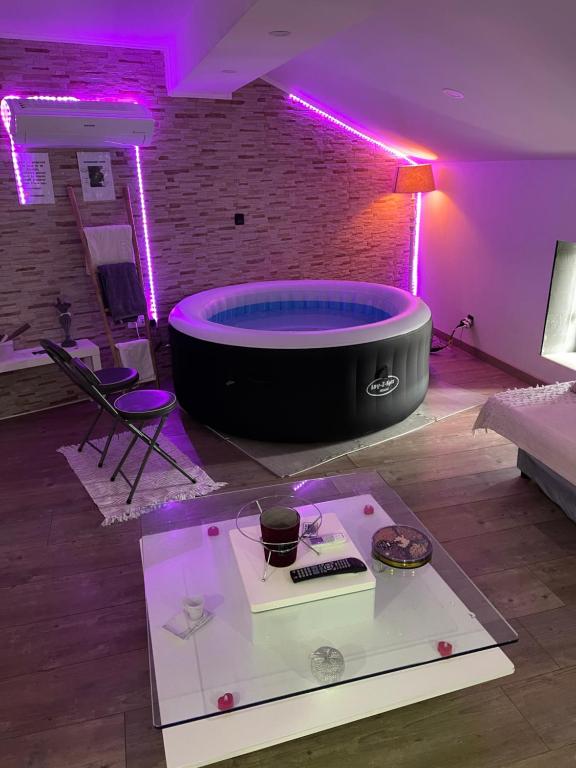 a room with a large tub in a room with purple lights at Love’Room in Trèbes