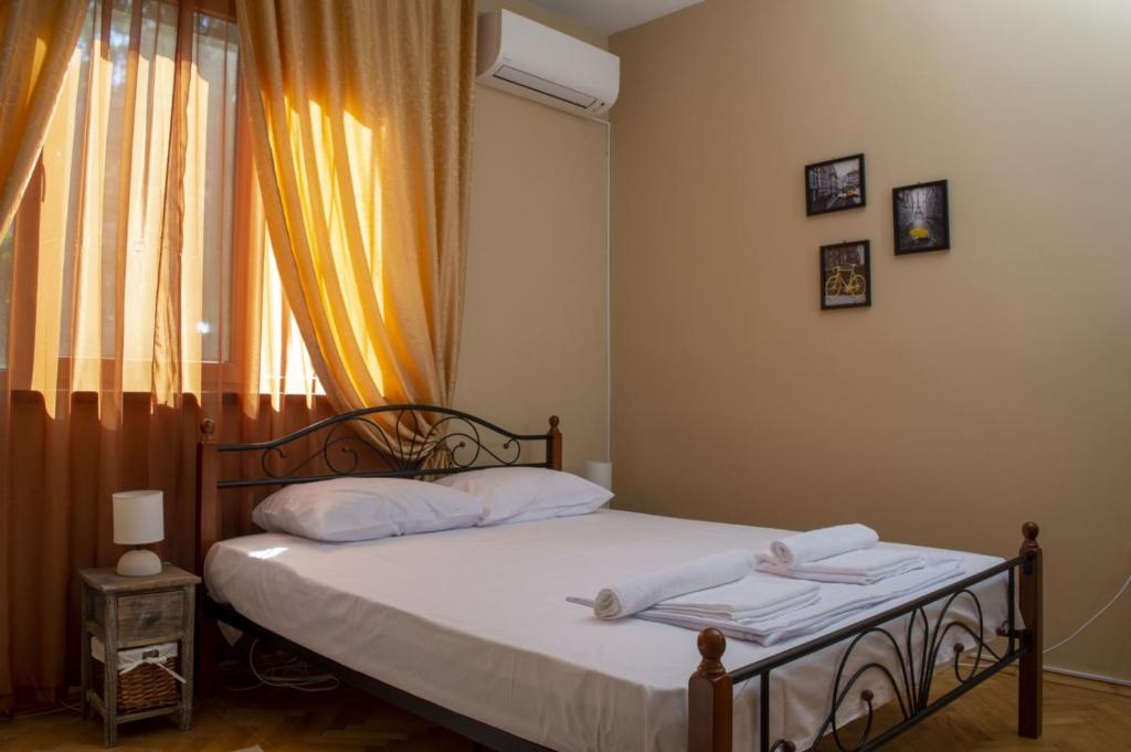 a bedroom with a bed with white sheets and a window at Midtown Place Apartment DORIS 1 with garage in Plovdiv