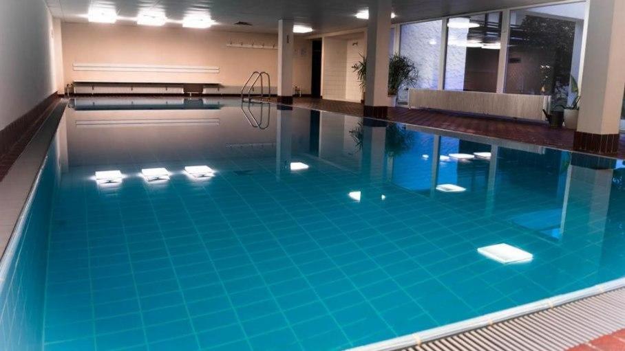 a large swimming pool with blue water in a building at Bergkristall - Freie Fahrt Allgäuer Hörnerbahnen im Sommer in Bolsterlang