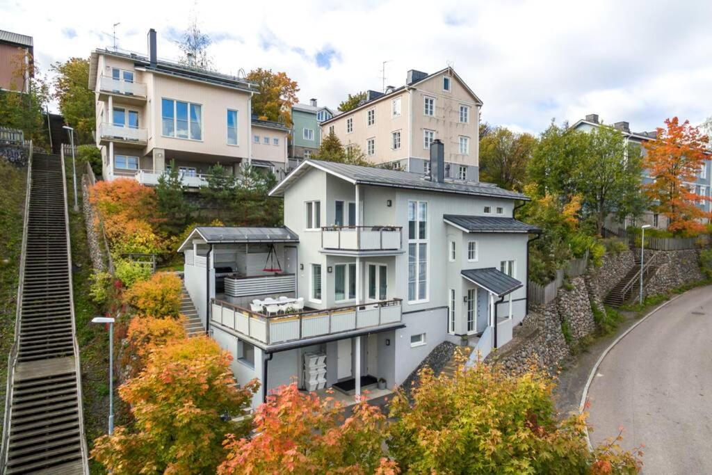 a building on the side of a hill with houses at Villa Rajaportti 1st&2nd floor Loft with lakeview and free front door parking with electric car plug in Tampere