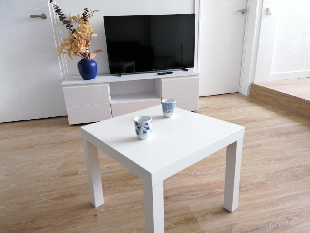 - une table basse blanche dans le salon avec une télévision dans l'établissement Les Marines, à Courseulles-sur-Mer