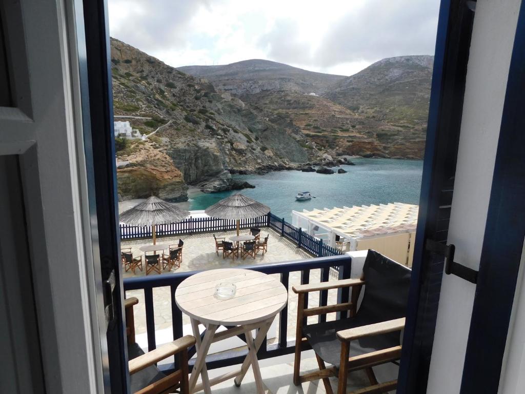 een balkon met een tafel en stoelen en een strand bij Pasithea Folegandros in Agali