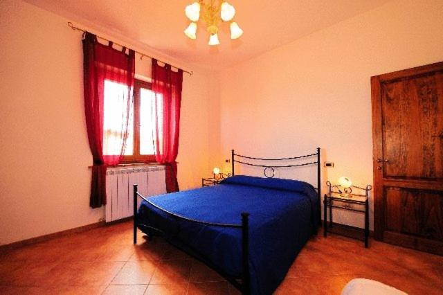 a bedroom with a blue bed and red curtains at Agriturismo Villa Martis in Passignano sul Trasimeno