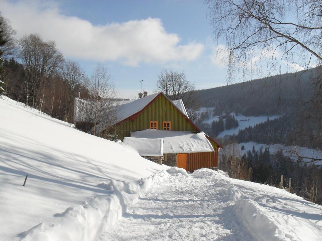 a large pile of snow next to a red barn at Penzion Pampeliška in Pec pod Sněžkou