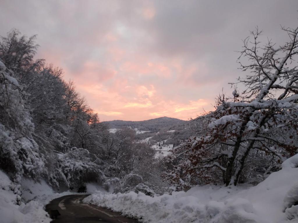 une route recouverte de neige avec le coucher du soleil en arrière-plan dans l'établissement La Ferme sous les Hiez, à Cornimont