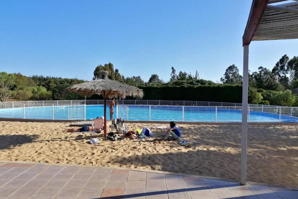un grupo de personas yaciendo en la arena cerca de una piscina en Casa de Costa, Campo y Relax, en Algarrobo