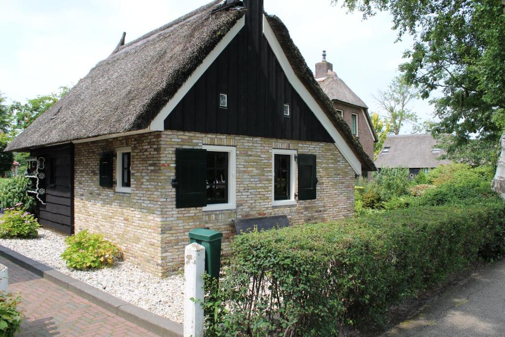 een klein bakstenen huis met een rieten dak bij Appartement Het Kleine Huisje met bedstee in Giethoorn