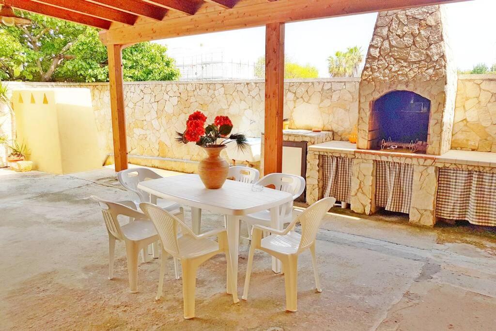 een witte tafel met stoelen en een vaas met bloemen erop bij Villetta sul Mare a Gallipoli Padula Bianca in Alezio