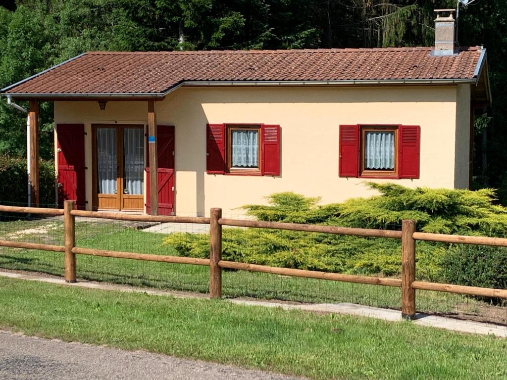 een klein huis met rode luiken en een hek bij GITE*** DES BARAQUES in Fontenoy-le-Château
