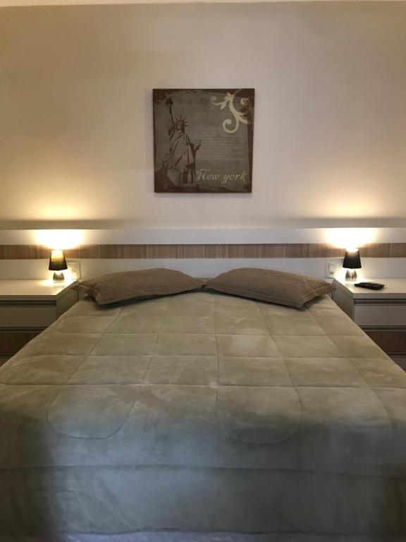 a bedroom with a large bed with two lights on it at Wall Street Flat Service in Caxias do Sul