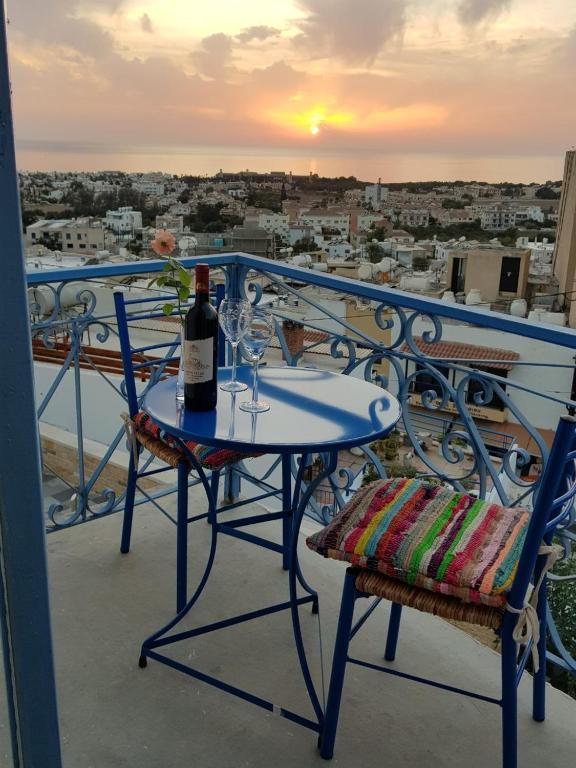 a table with a bottle of wine and two chairs on a balcony at Town Apartment with panoramic seaview in Paphos