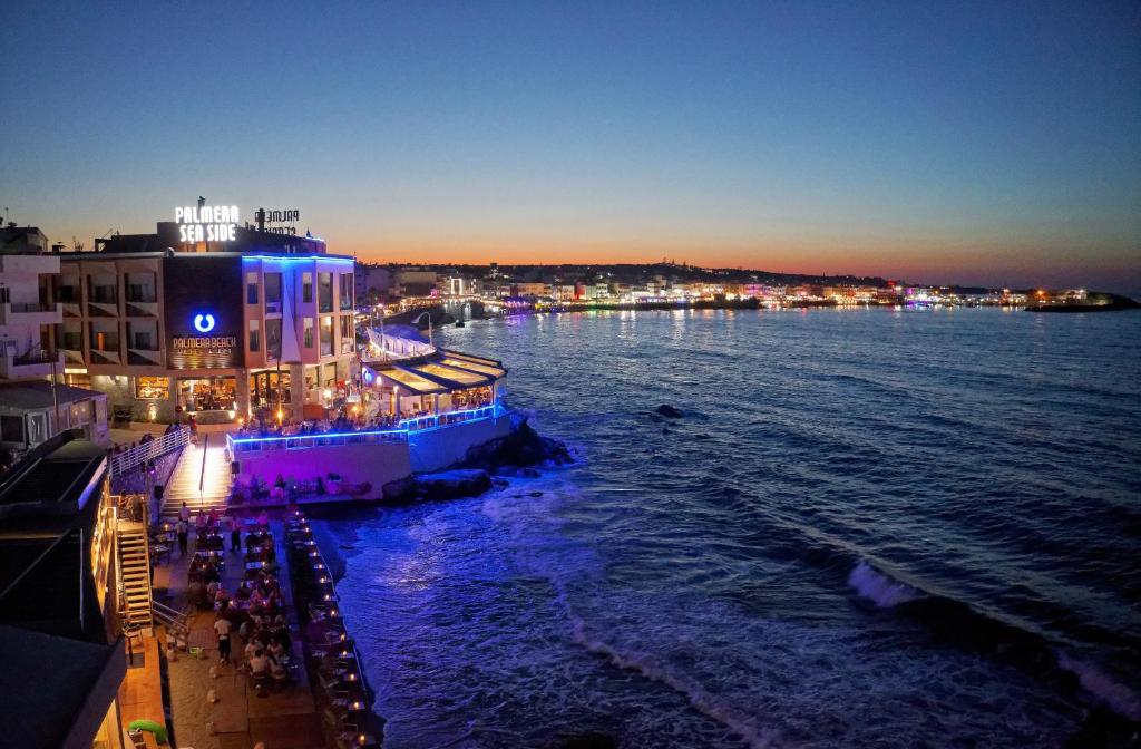 a night view of a pier with a building and the water at Palmera Beach Hotel & Spa - Adults Only in Hersonissos