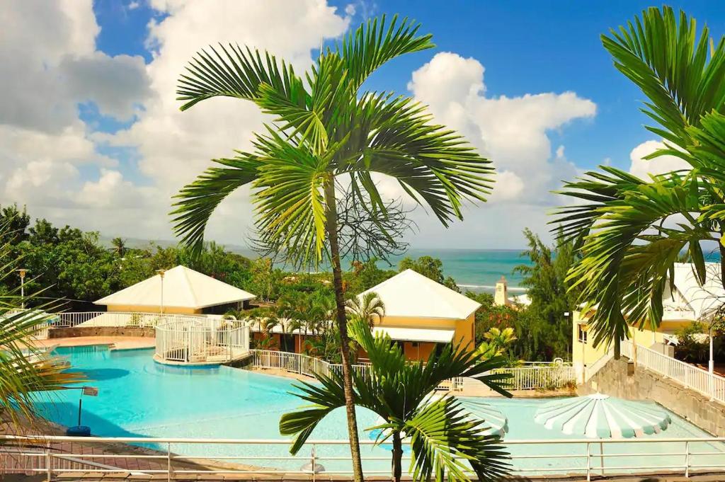 un complejo con una palmera y una piscina en Résidence de la baie 2 - BLEU SOLEIL TARTANE, en La Trinité