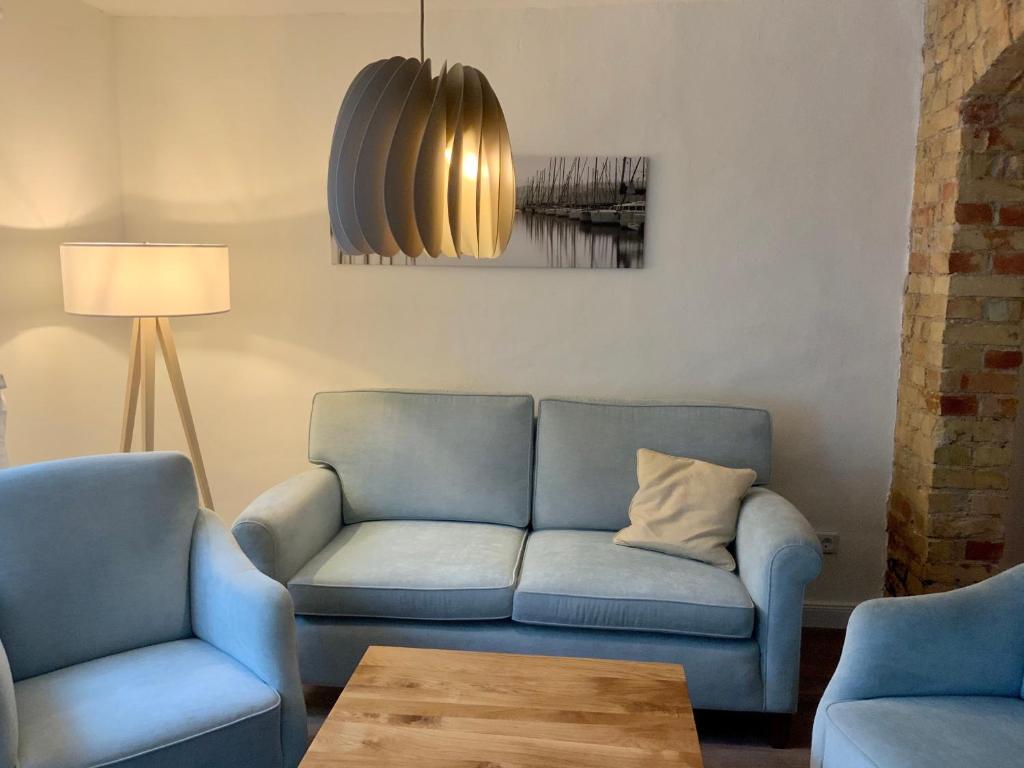 a living room with a blue couch and a table at FeWoEck Kogge in Eckernförde