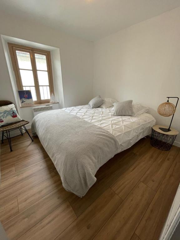 a white bedroom with a bed and a wooden floor at Appartement idéalement situé Ax-les-thermes in Ax-les-Thermes
