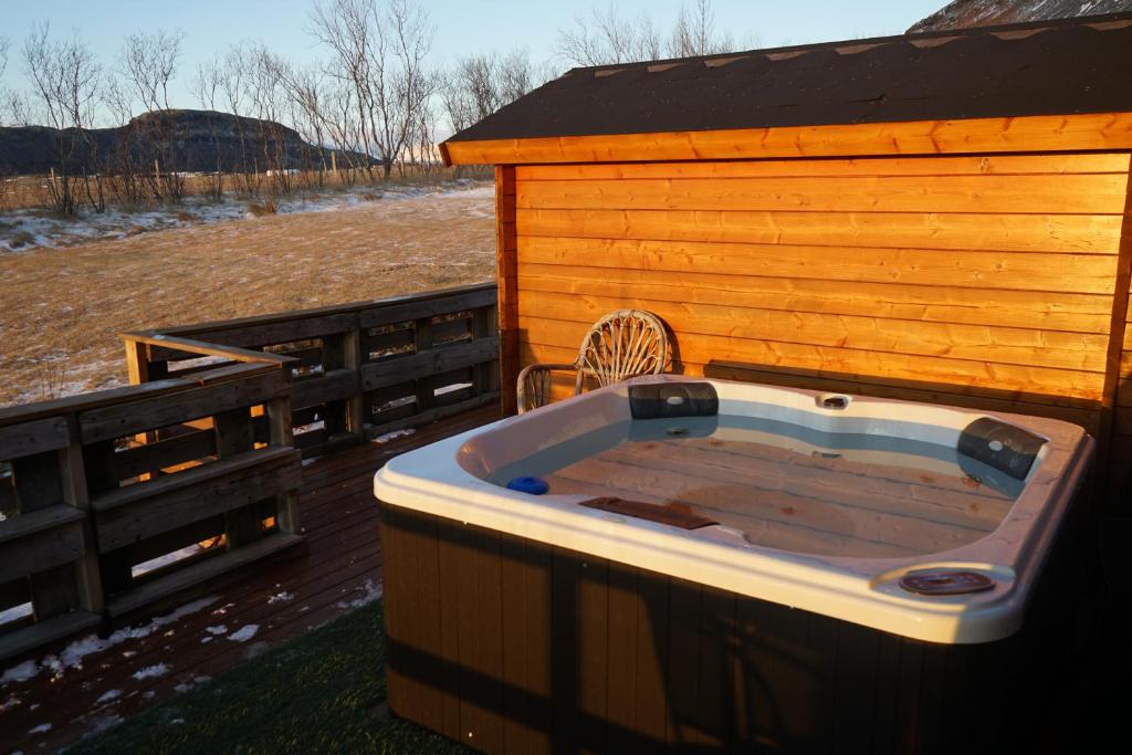bañera de hidromasaje junto a un edificio de madera en Guesthouse Birkifell, en Nesjum