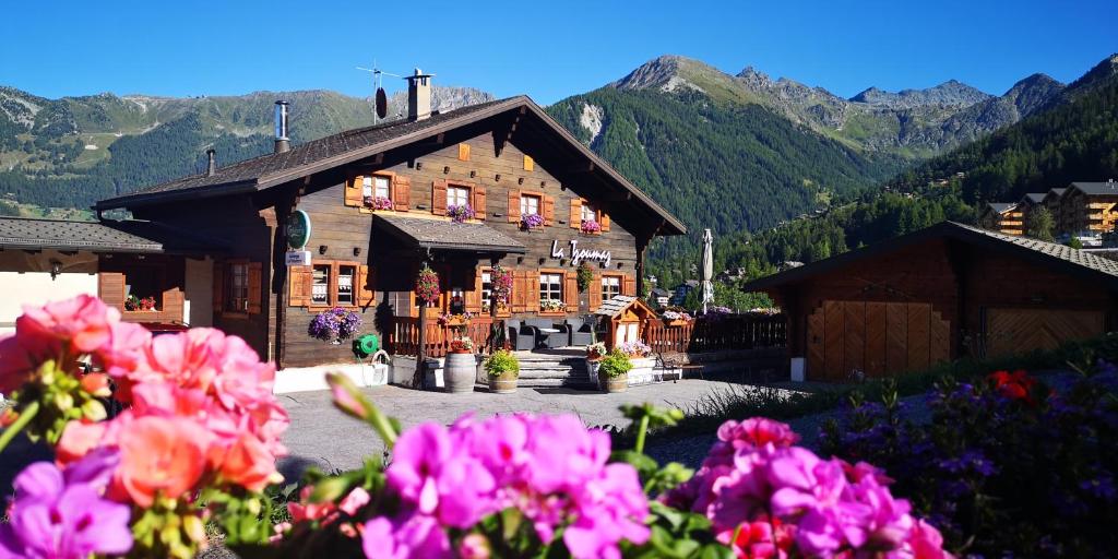 un gran edificio de madera con flores delante en Auberge la Tzoumaz en La Tzoumaz