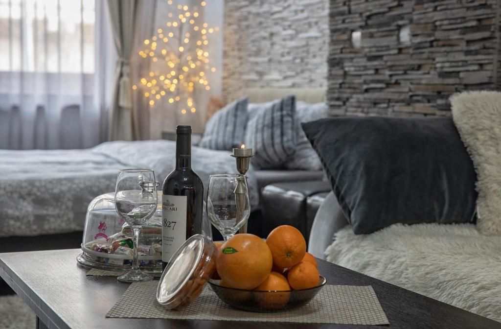un tavolo con una ciotola di arance e una bottiglia di vino di Studio Enis a Poiana Brasov