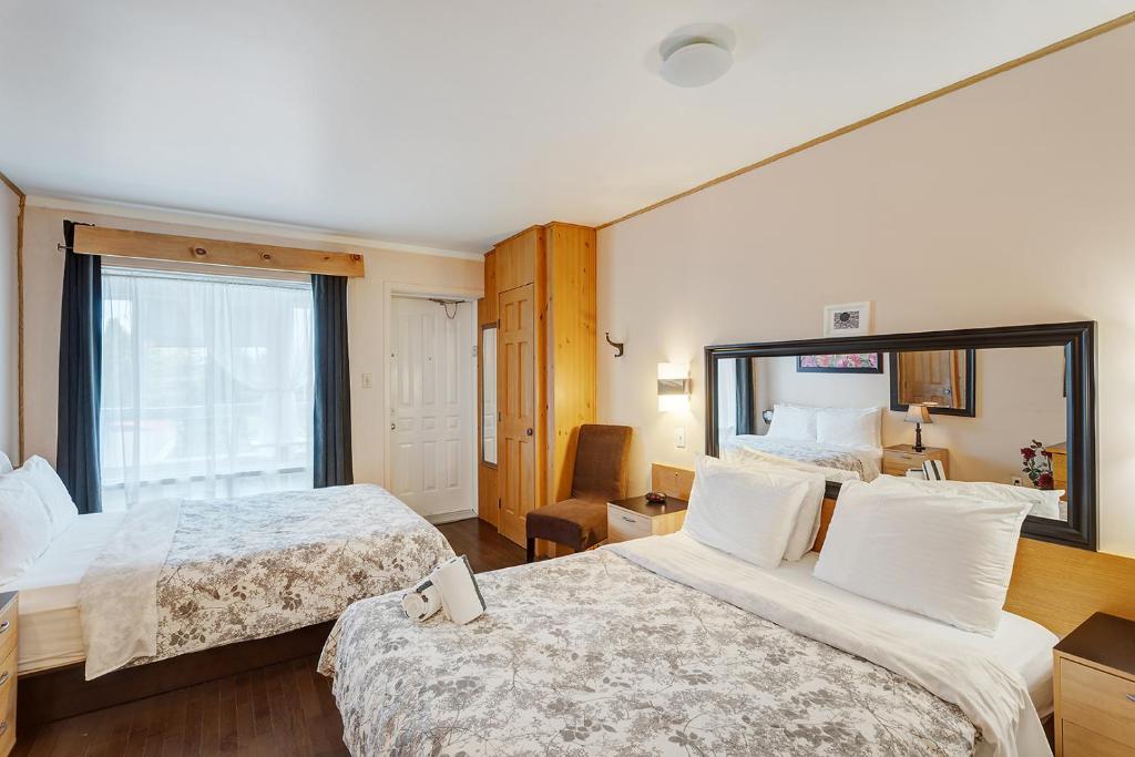 a hotel room with two beds and a window at Auberge Hotel Spa Watel in Sainte-Agathe-des-Monts
