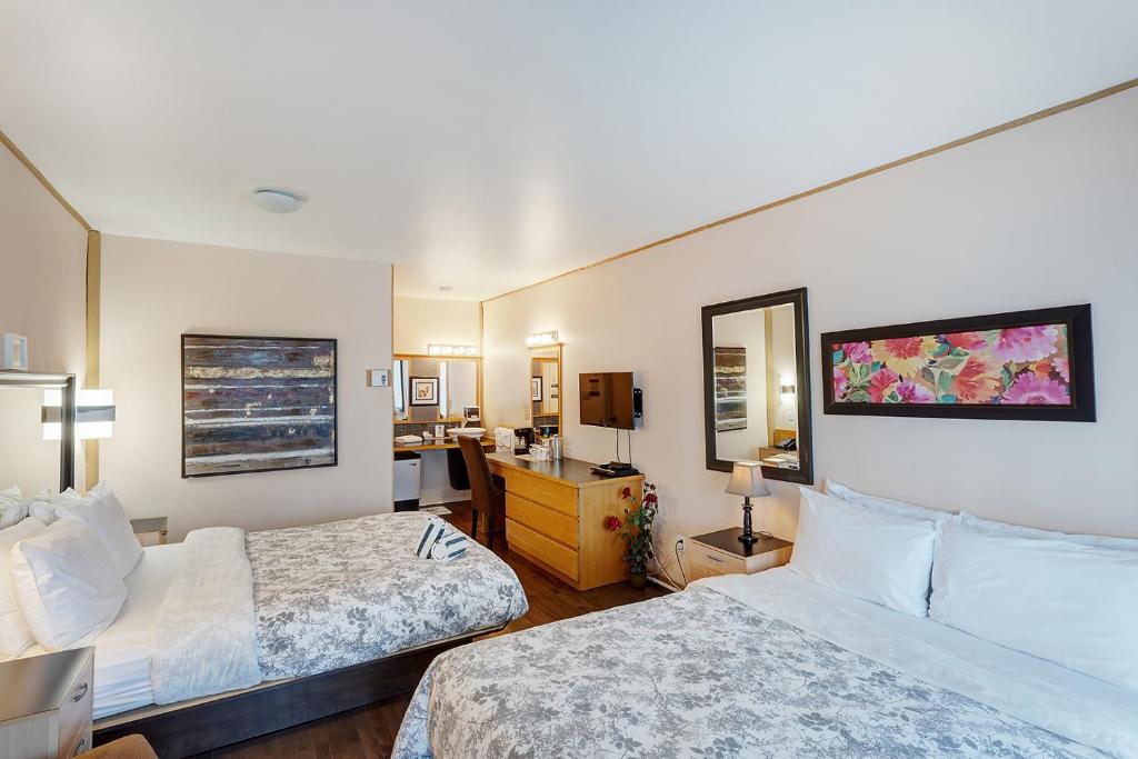 a hotel room with two beds and a desk at Auberge Hotel Spa Watel in Sainte-Agathe-des-Monts