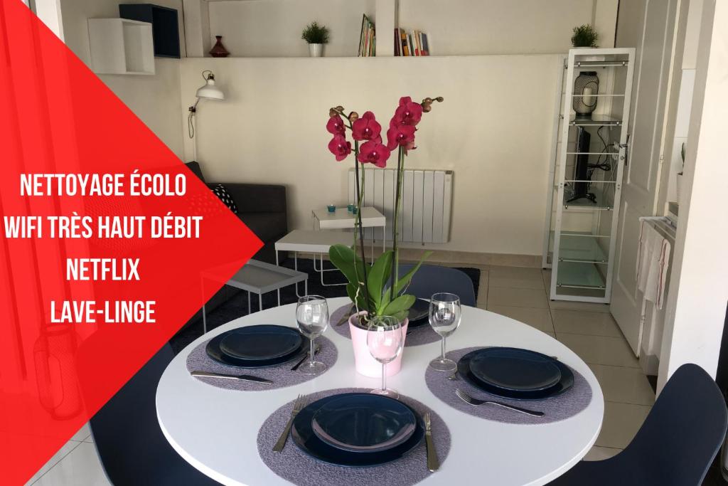 einen weißen Tisch mit schwarzen Platten und eine Vase mit Blumen in der Unterkunft Saclay - Green and premium flat close Paris - WIFI & NETFLIX in Saclay