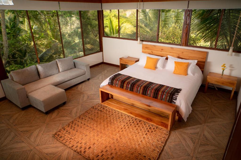 1 dormitorio con cama, sofá y ventanas en Casa Olonche, en Olón