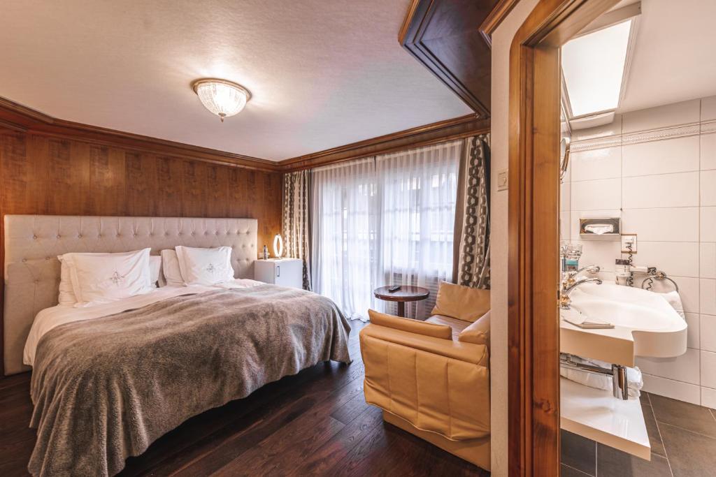 a bedroom with a bed and a sink and a chair at Boutique Hotel Albana Real - Restaurants & Spa in Zermatt