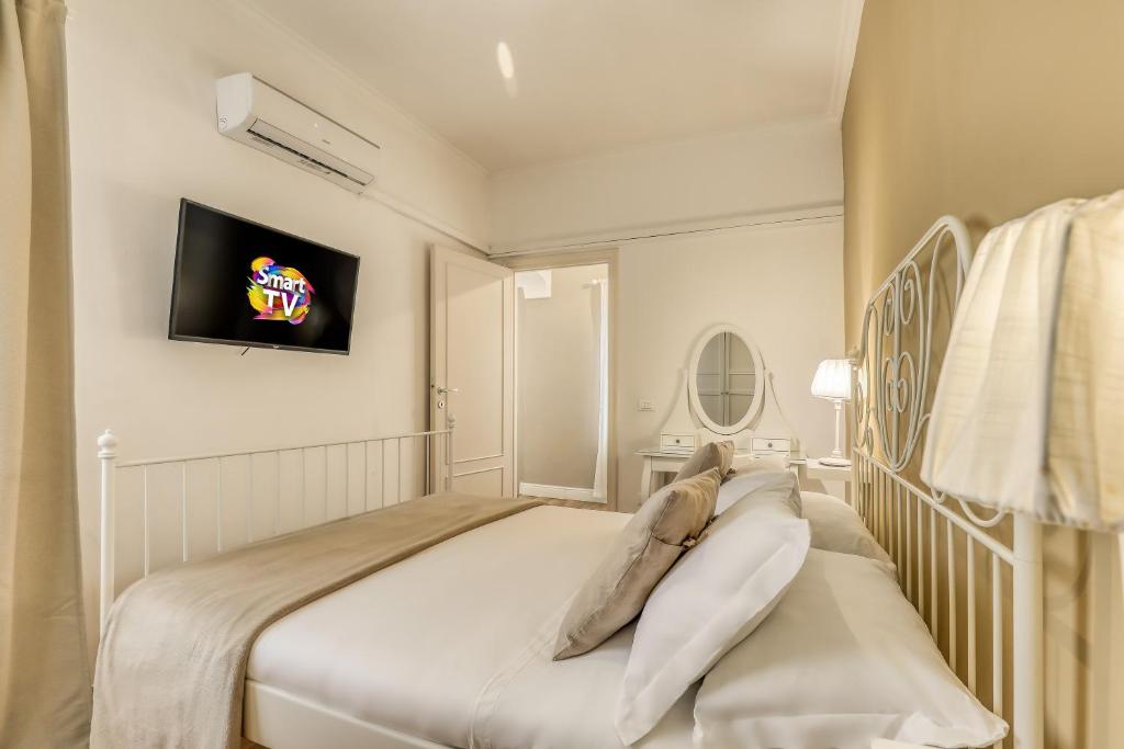 een witte slaapkamer met een bed en een tv aan de muur bij ATRHOME penthouse Frattina in Rome