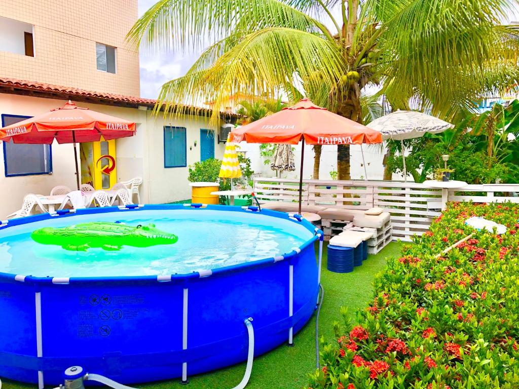 una bañera de hidromasaje en un patio con sombrillas y flores en Ótima Localização casa, 7 quartos-Porto de Galinhas 900m piscinas naturais en Porto De Galinhas