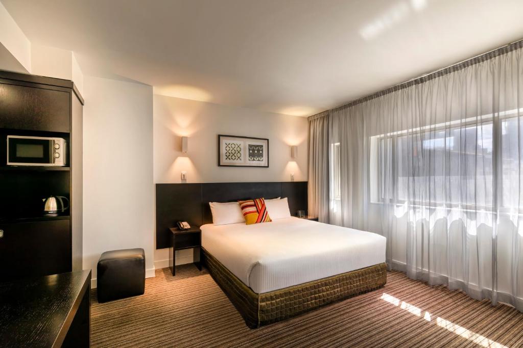 a bedroom with a large bed and a large window at Causeway 353 Hotel in Melbourne