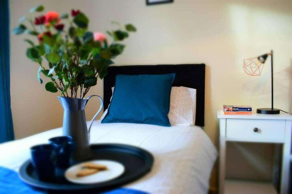 a tray with a plate and a vase with flowers on a bed at Comfortable Apartment in Sheffield with Parking in Neepsend