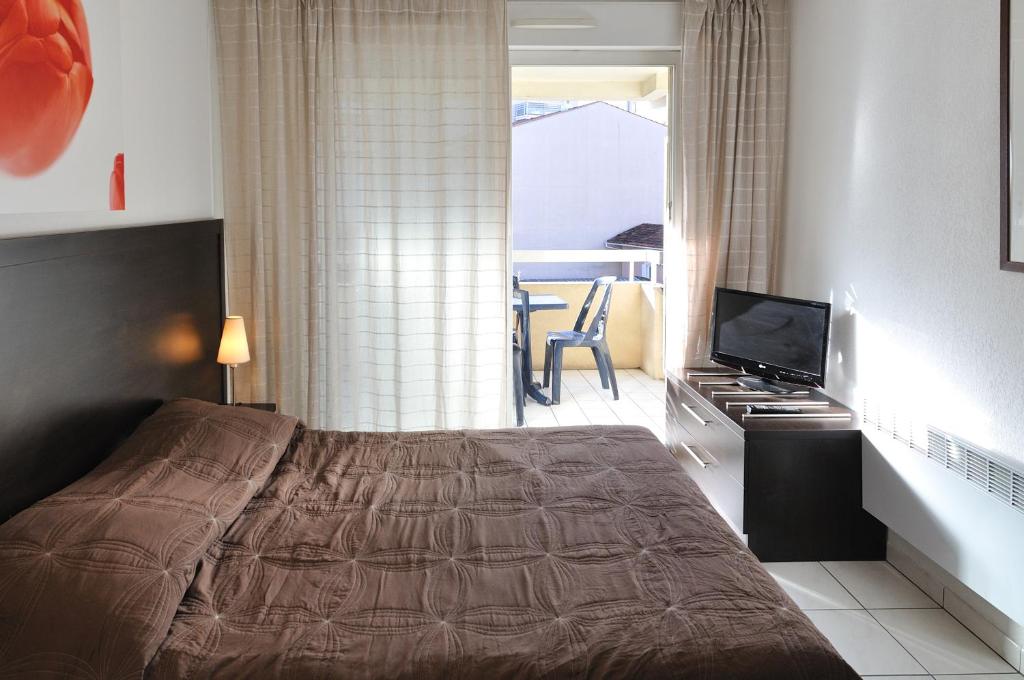a bedroom with a bed and a television and a balcony at Residhotel Cannes Festival in Cannes