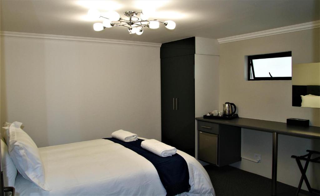 sypialnia z łóżkiem i biurkiem z ręcznikami w obiekcie Mahem Manor Guesthouse w mieście Brits