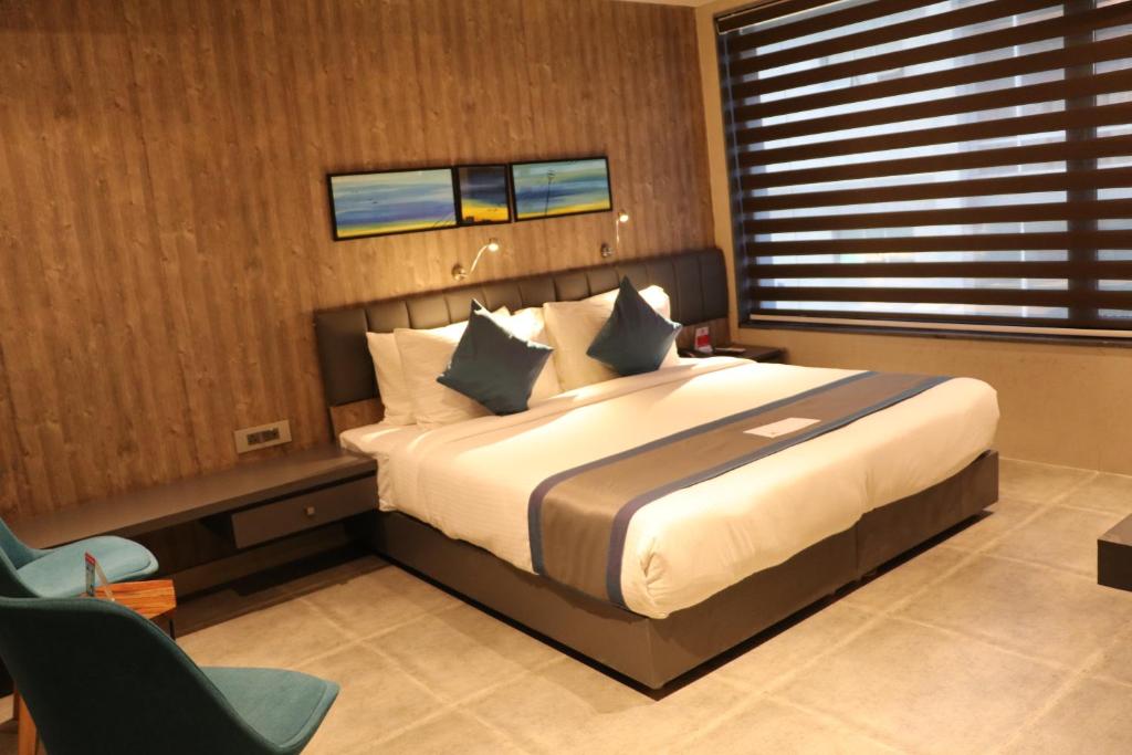 een slaapkamer met een groot bed en een stoel bij The Soni'otel in Howrah