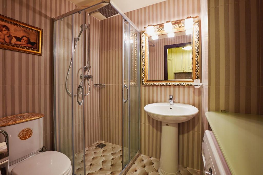 ein Bad mit einer Dusche, einem Waschbecken und einem WC in der Unterkunft Apartments Lux in city center Lviv in Lwiw
