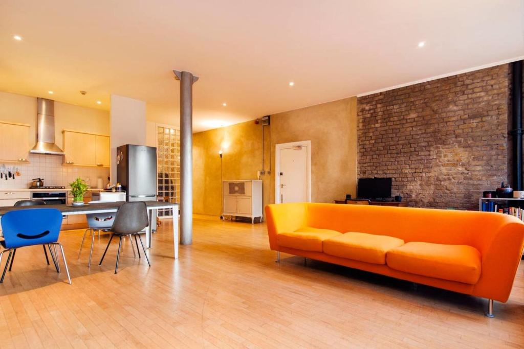 ロンドンにあるGuestReady - Bright Studio in the Heart of Londonのリビングルーム(オレンジ色のソファ付)、キッチンが備わります。