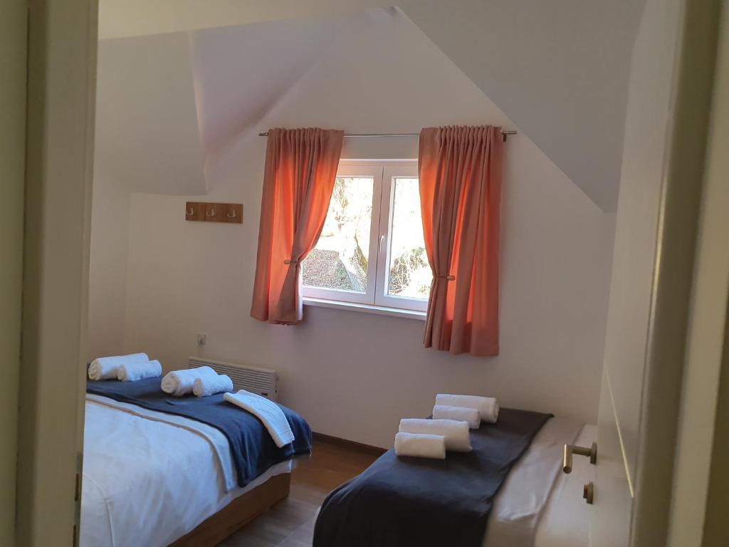 a bedroom with a bed and a window with orange curtains at Vila Vrh in Crni Vrh