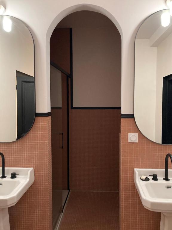 a bathroom with two sinks and two mirrors at Au Petit Thouars in Thouars