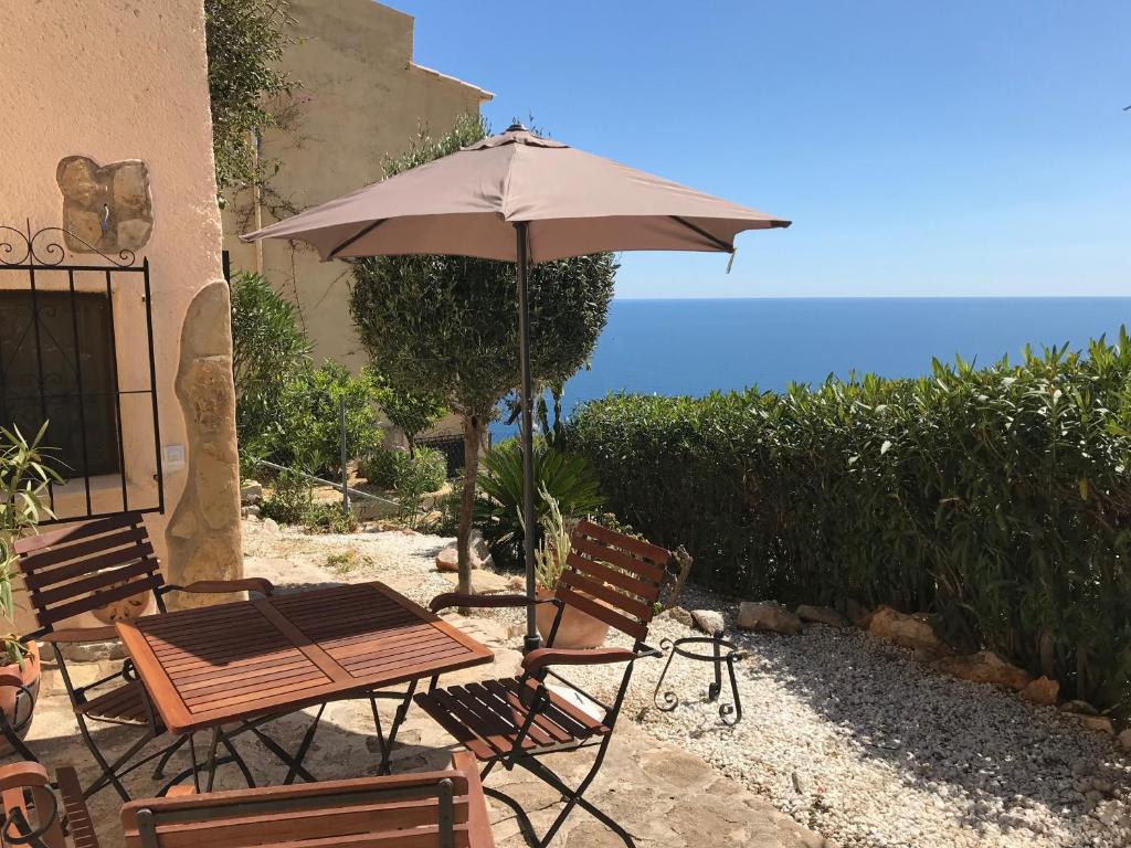 einen Tisch und Stühle mit einem Sonnenschirm und dem Meer in der Unterkunft Casa Esperanza in Benitatxell
