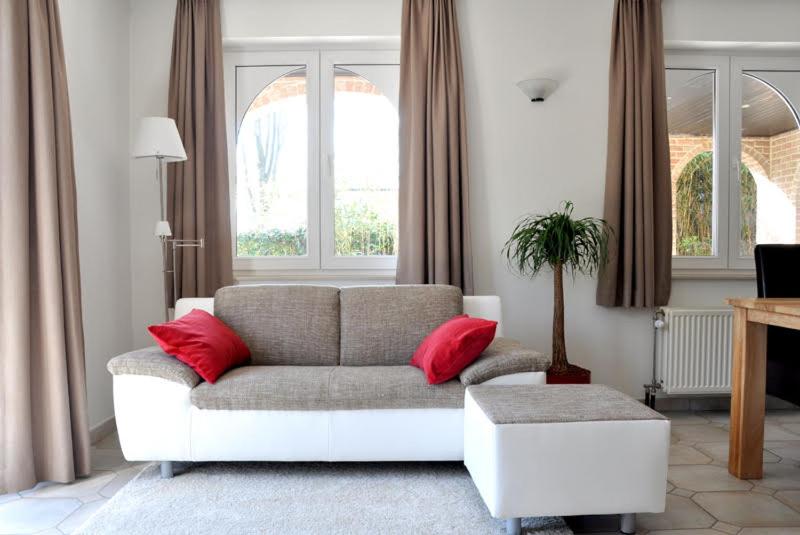 B Apartment في Bierbeek: غرفة معيشة مع أريكة ووسائد حمراء