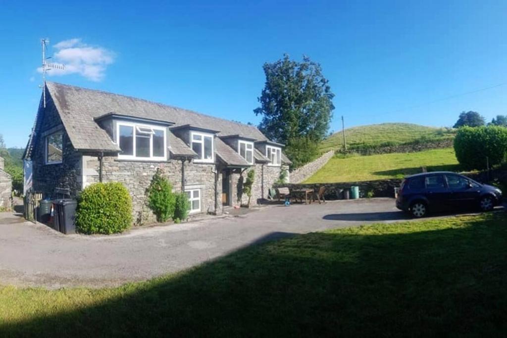 Beautiful 3-bed stone barn in idyllic Hawkshead في هوكسهيد: منزل فيه سيارة متوقفة أمامه