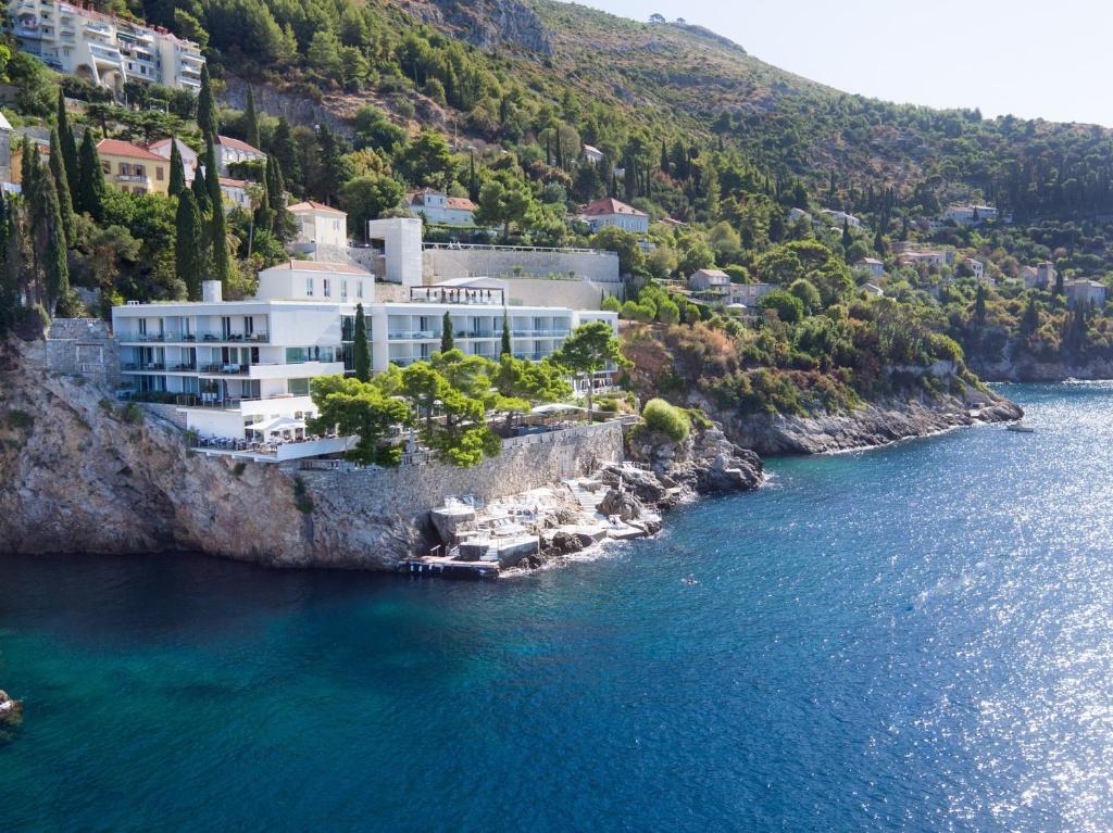 a building on a cliff next to the water at Villa Dubrovnik in Dubrovnik