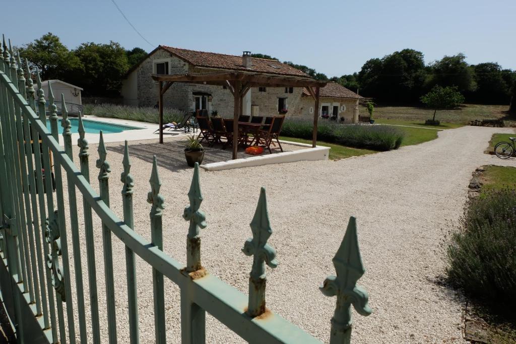 einen Zaun vor einem Haus mit Pool in der Unterkunft Les Portes Vertes in Mairé-lʼEvescault