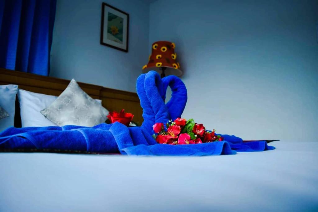 una cama con un peluche azul y flores en ella en Pailin Hotel, en Klong Muang Beach