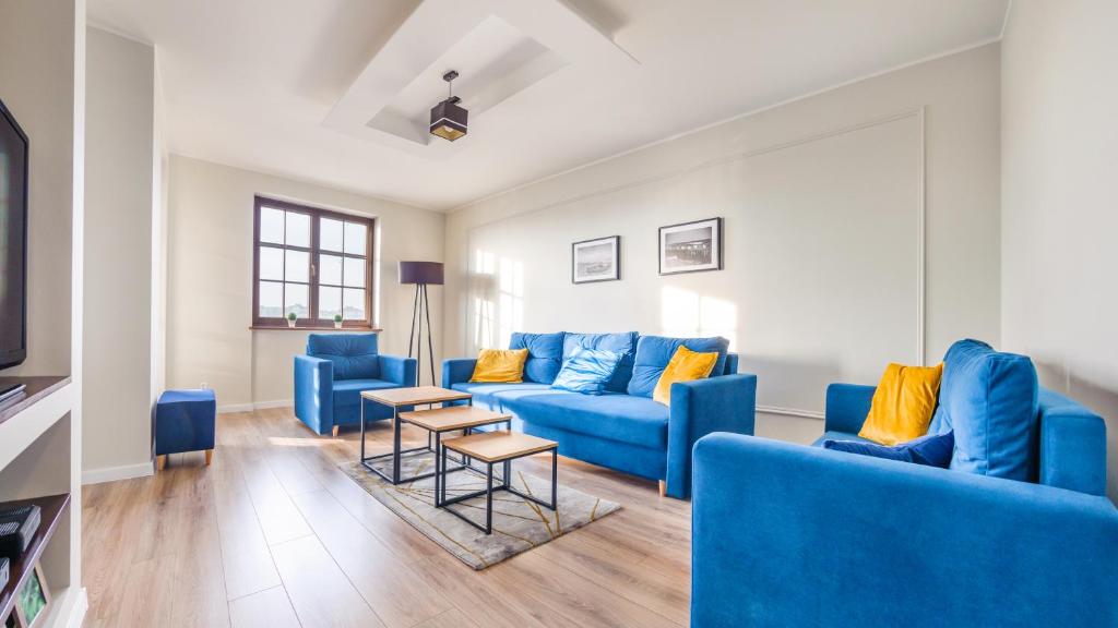 a living room with blue couches and yellow pillows at Apartamenty Sun & Snow Bulwar Portowy in Ustka