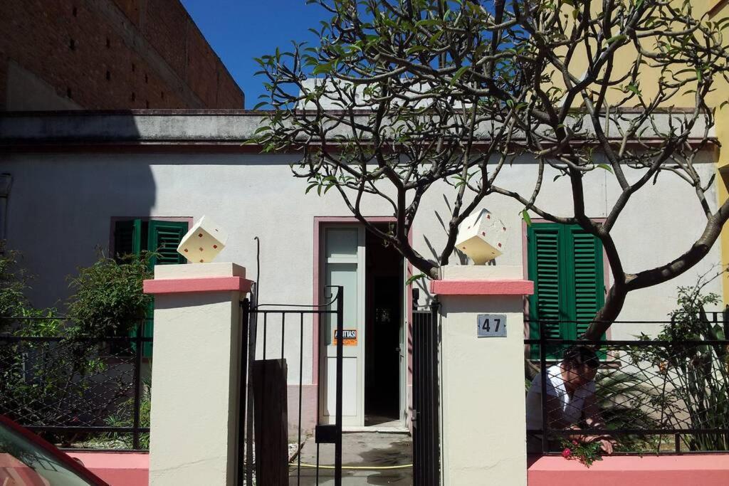 een wit gebouw met groene luiken en een boom bij La casa Dei Dadi in Milazzo