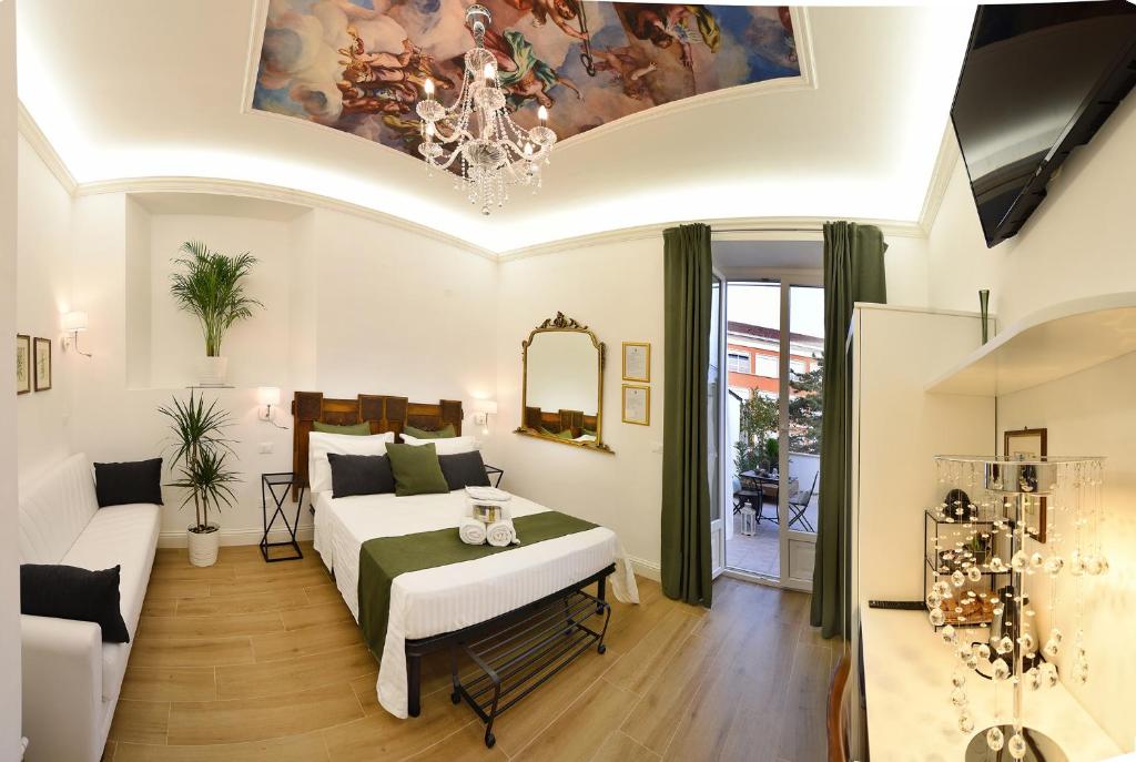 een slaapkamer met een bed, een bank en een kroonluchter bij Vittorio Veneto Private SPA in Sulmona